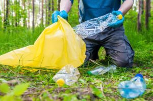 man cleaning up plastic pollution in forest