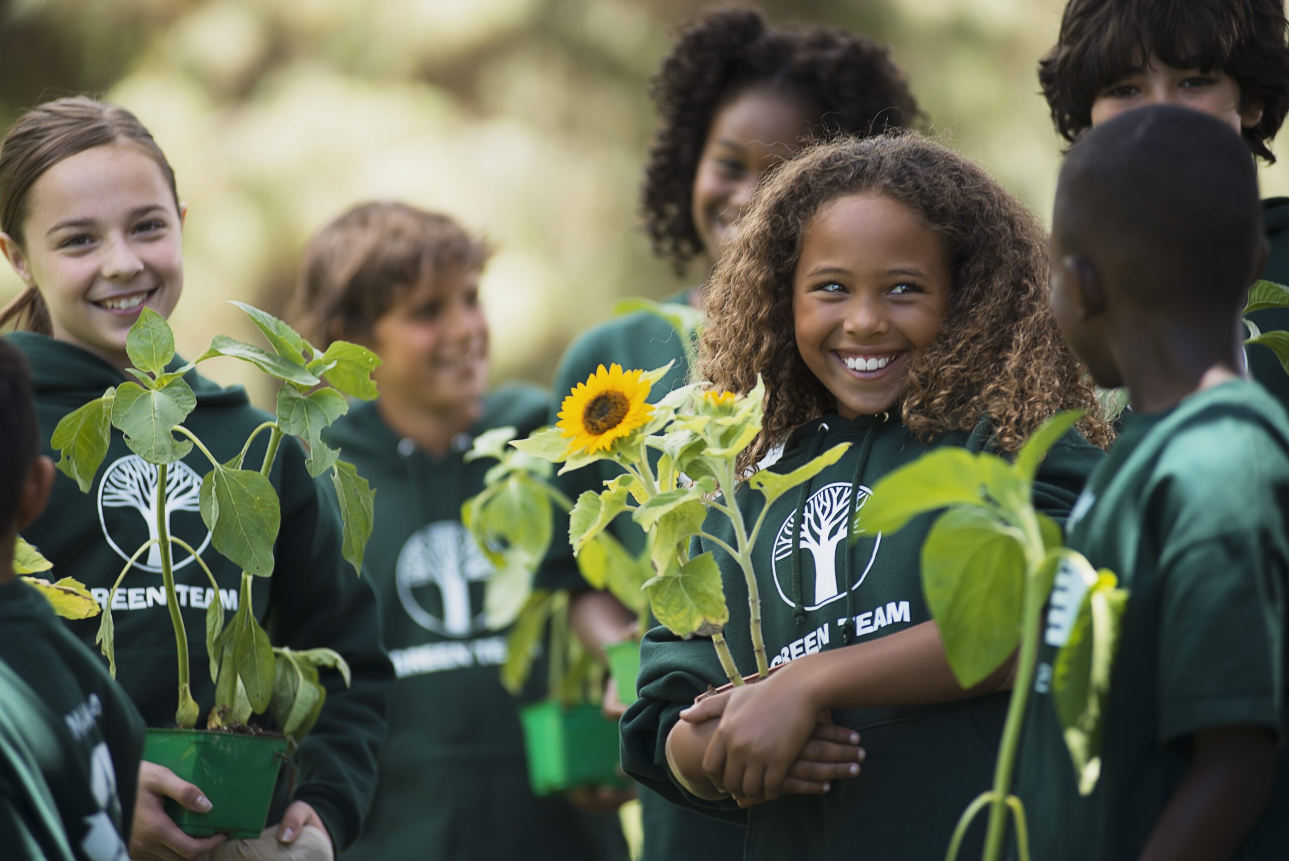 USA,Children in a group learning about plants and flowers, carrying plants and sunflowers. children during a volunteer event for Earth Day