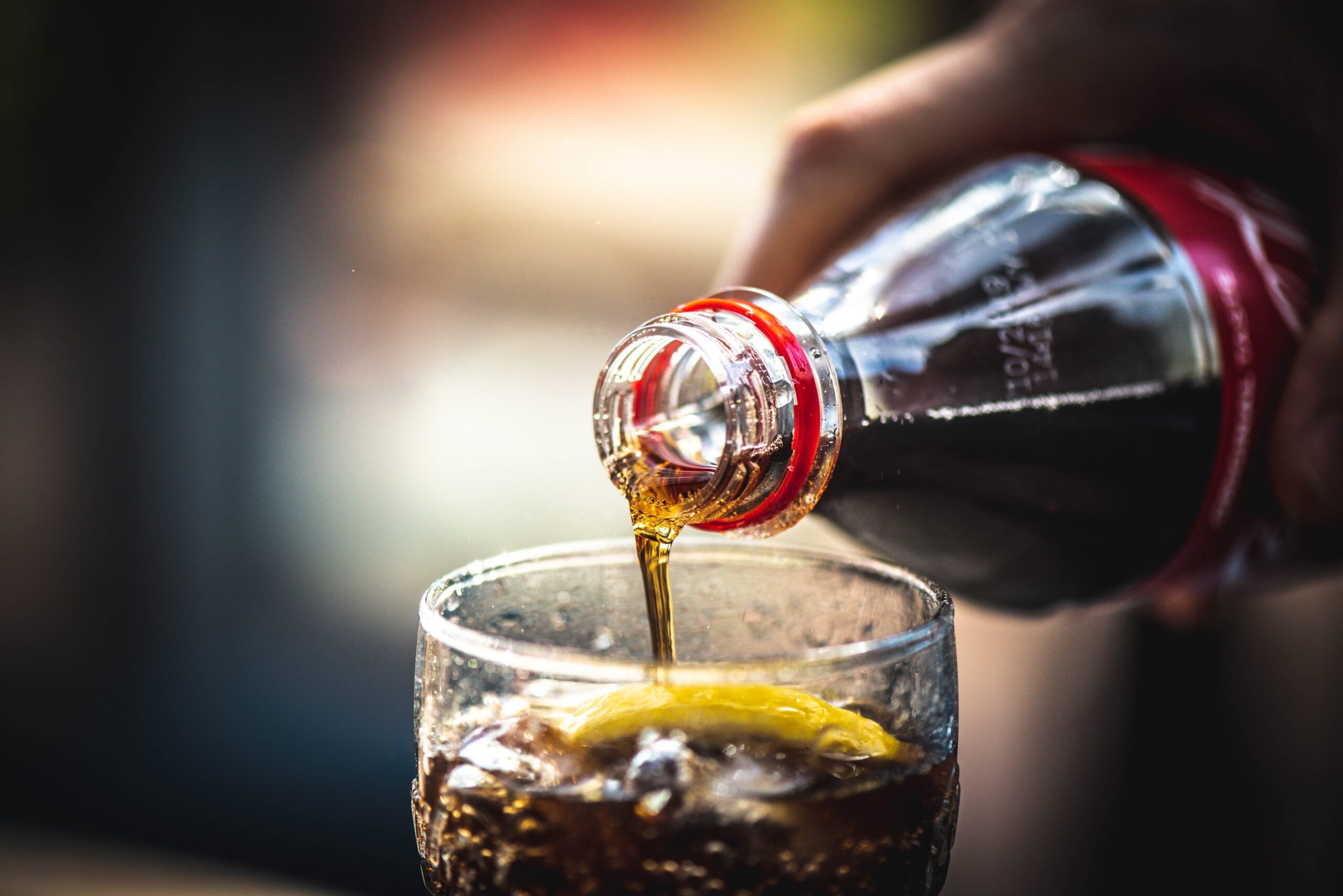 coca cola bottled beverage being poured into glass coca cola bottled beverage being poured into glass