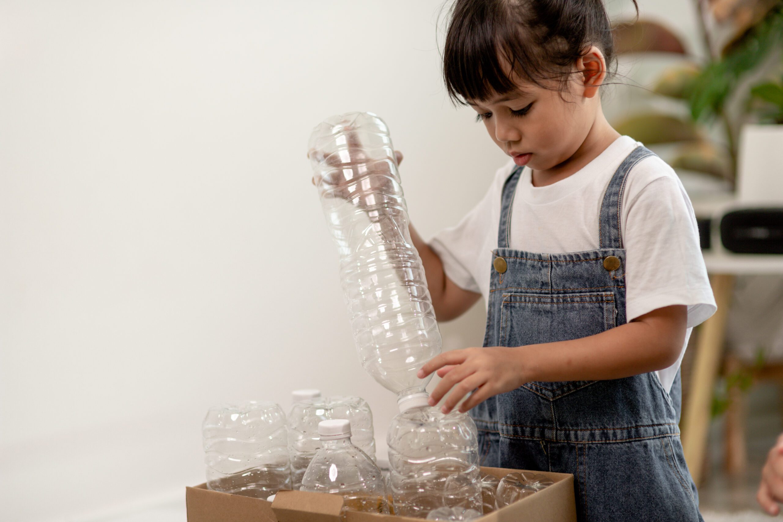 Little Girl holding plastic bottles for recycling little girl going through recyclable plastic bottle bin