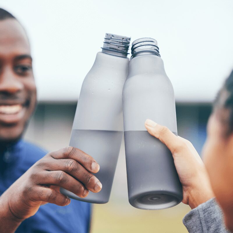 fitness water bottles and black couple toasting outdoors